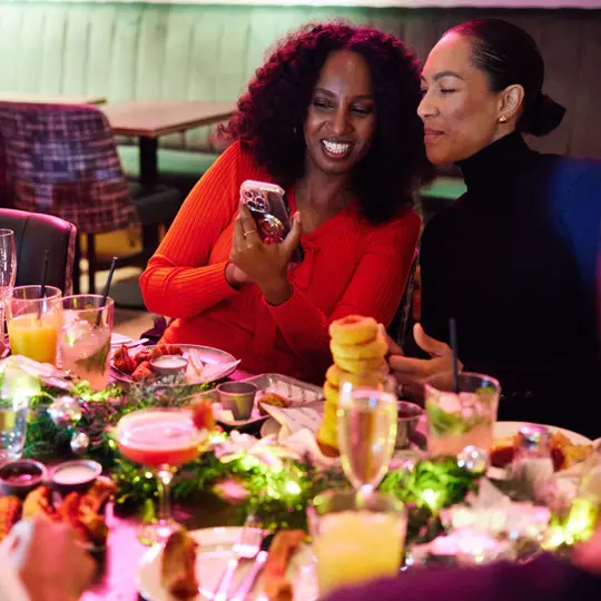 Two people looking at a phone over a festive table setting at SOUND London